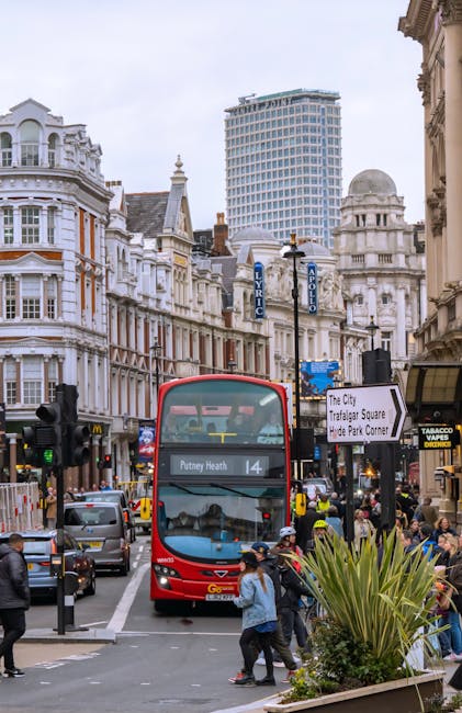 Street view of a busy area in Harringay with a double-decker bus displaying 'Putney Heath' on its front, surrounded by pedestrians crossing the road and waiting at the bus stop. The background feature