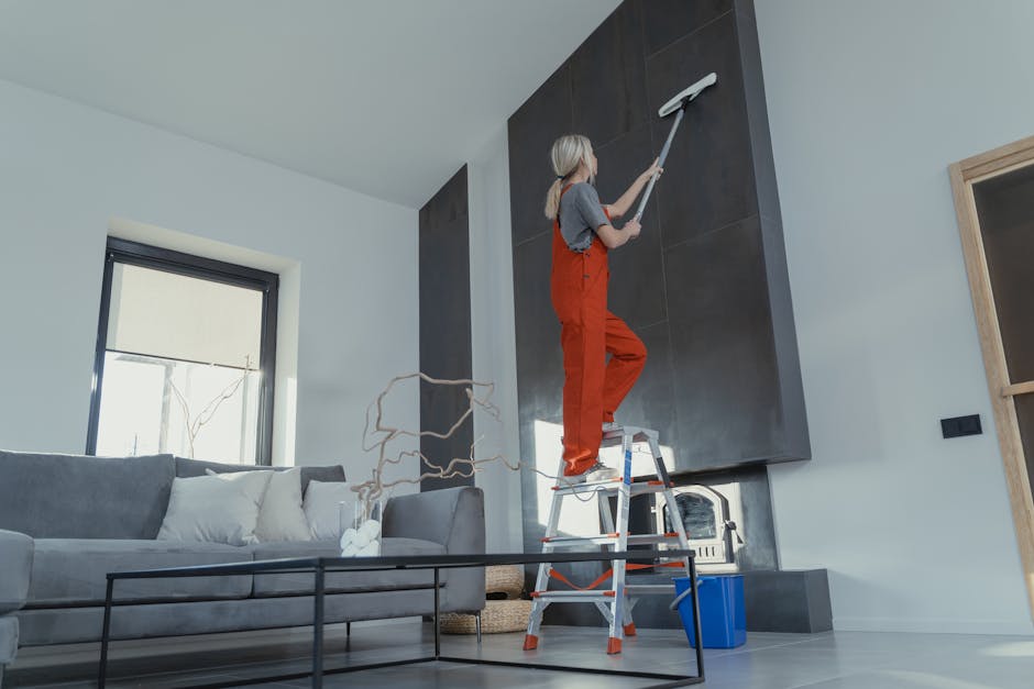 A wooden step ladder with paint splatters and signs of wear is positioned in a room with white walls and a wooden floor. Behind the ladder, there is a blue drop cloth spread on the floor, covering par